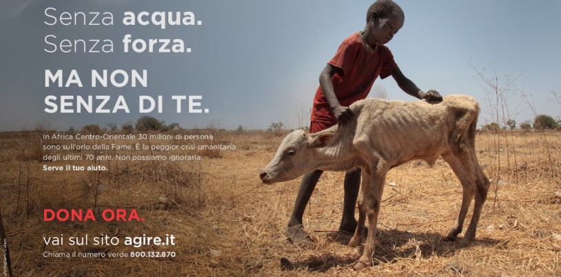 Un bambino africano accarezza un vitello denutrito